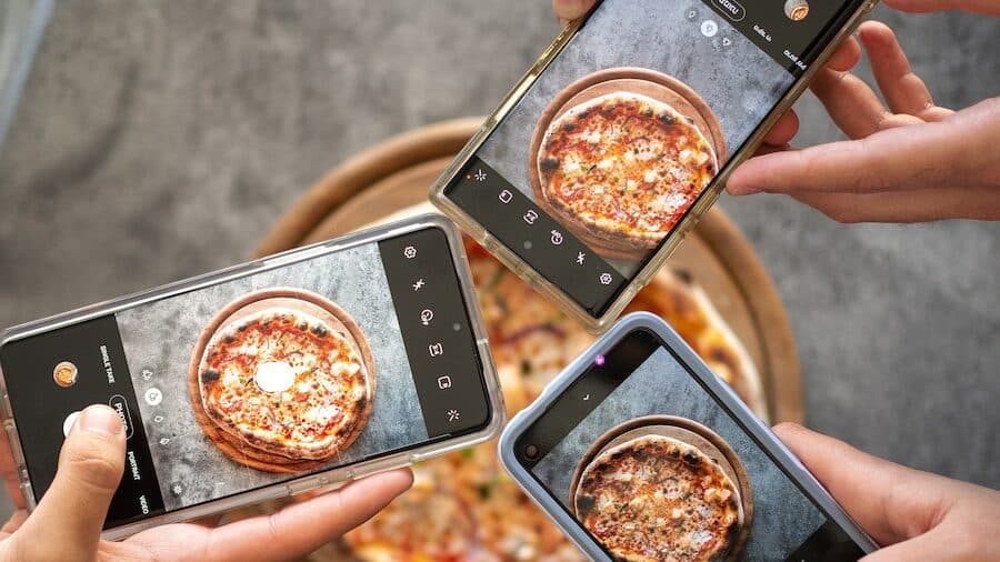 person holding black smartphone taking photo of pizza